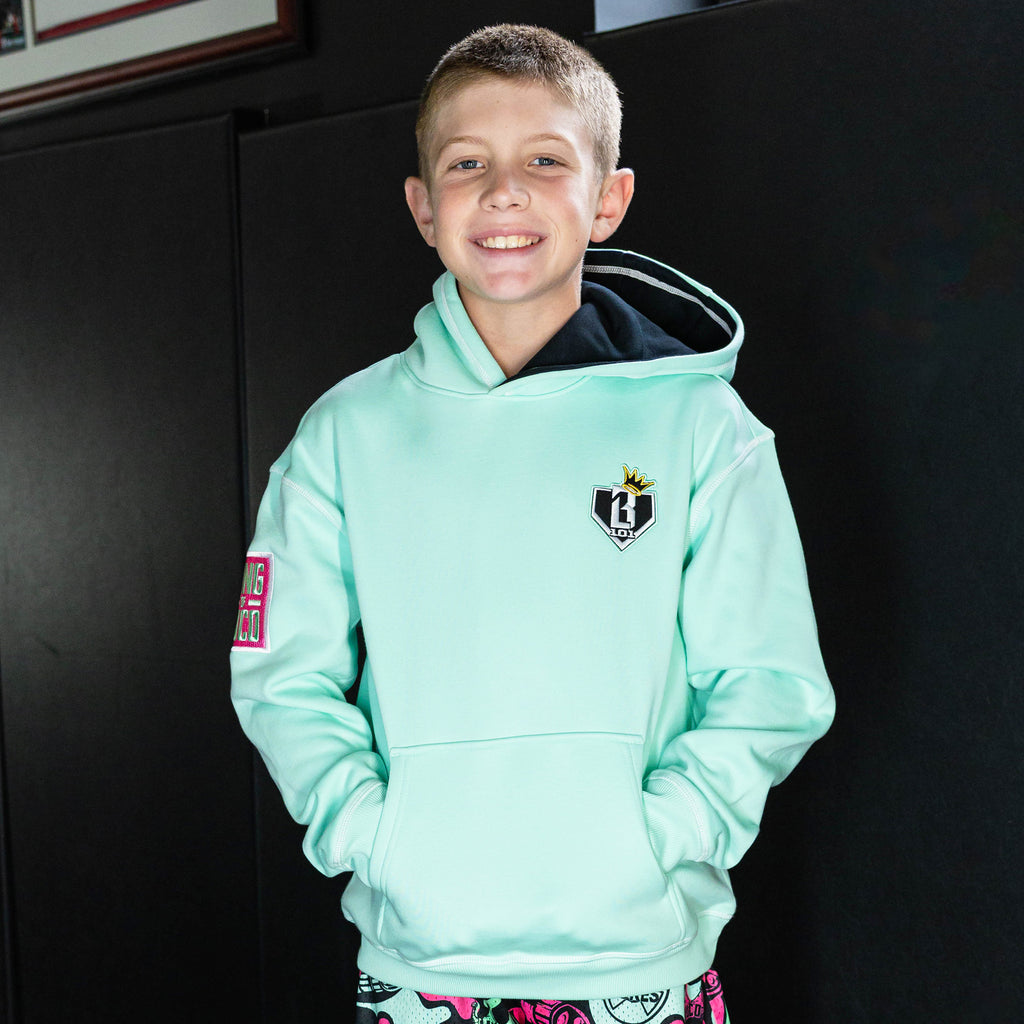 Youth model wearing teal hoodie with "King Of JUCO" design