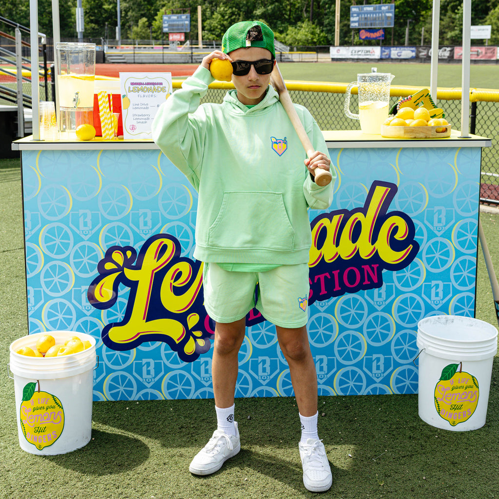 Youth model wearing green youth hoodie with "Lemonade" design