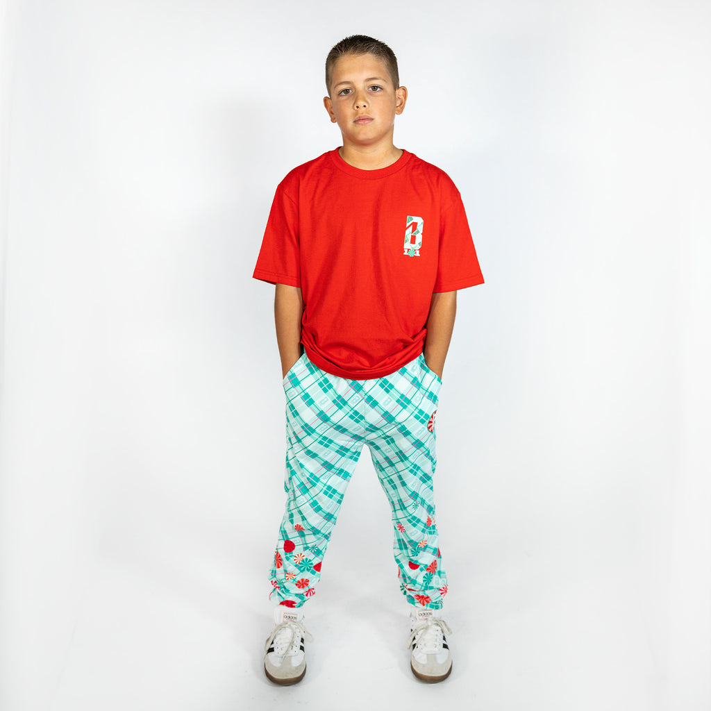 Youth model wearing multi-color youth pajama pants with "Peppermint Plaid" design