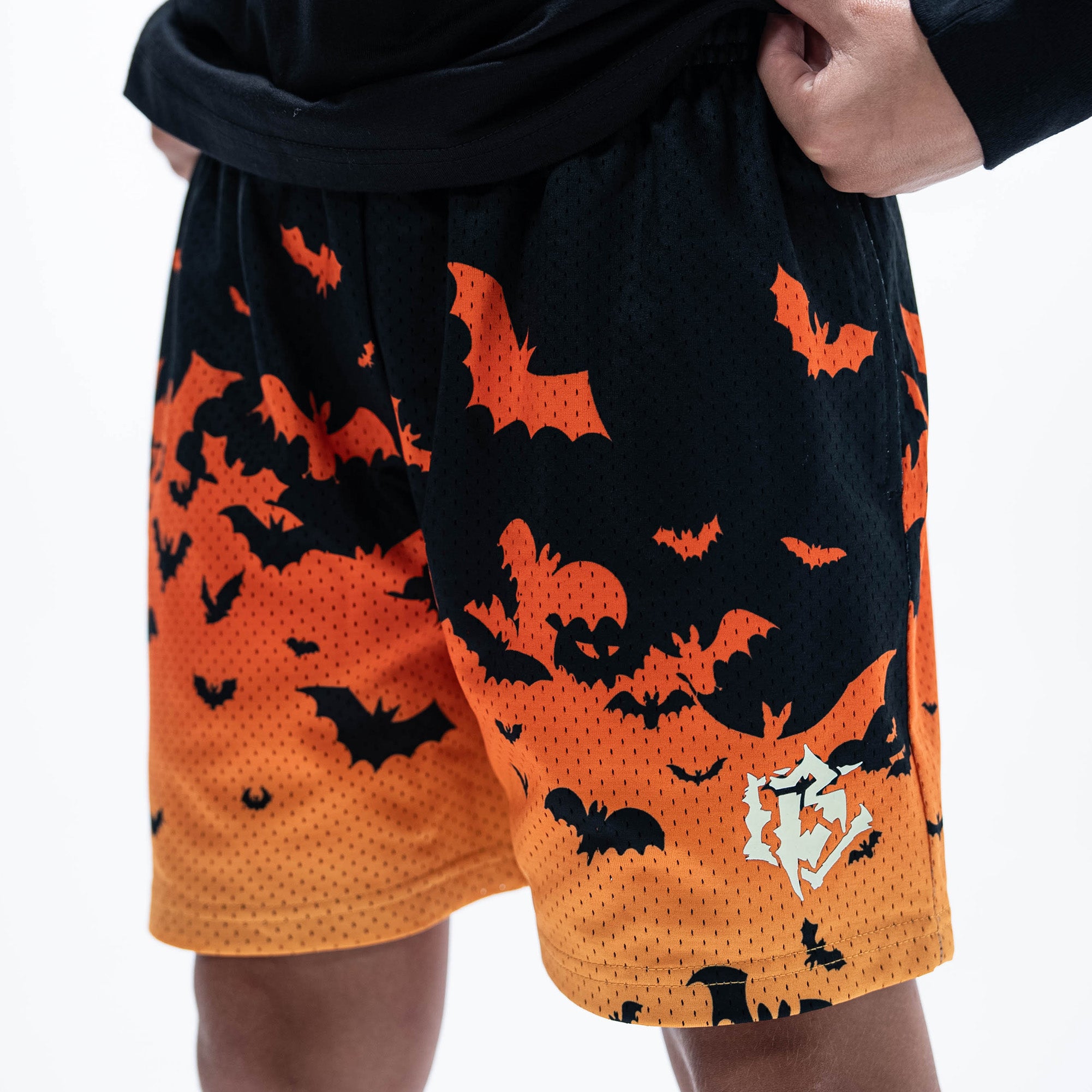 Youth model wearing orange youth shorts with "Bat Gradient" design
