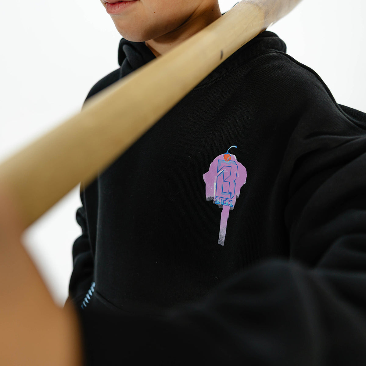 Youth model wearing black youth hoodie with "Fastball Scoops" design
