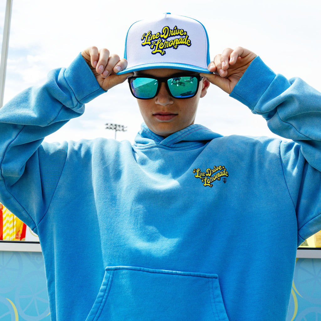 Youth model wearing blue youth hoodie with "Lemonade Cup" design