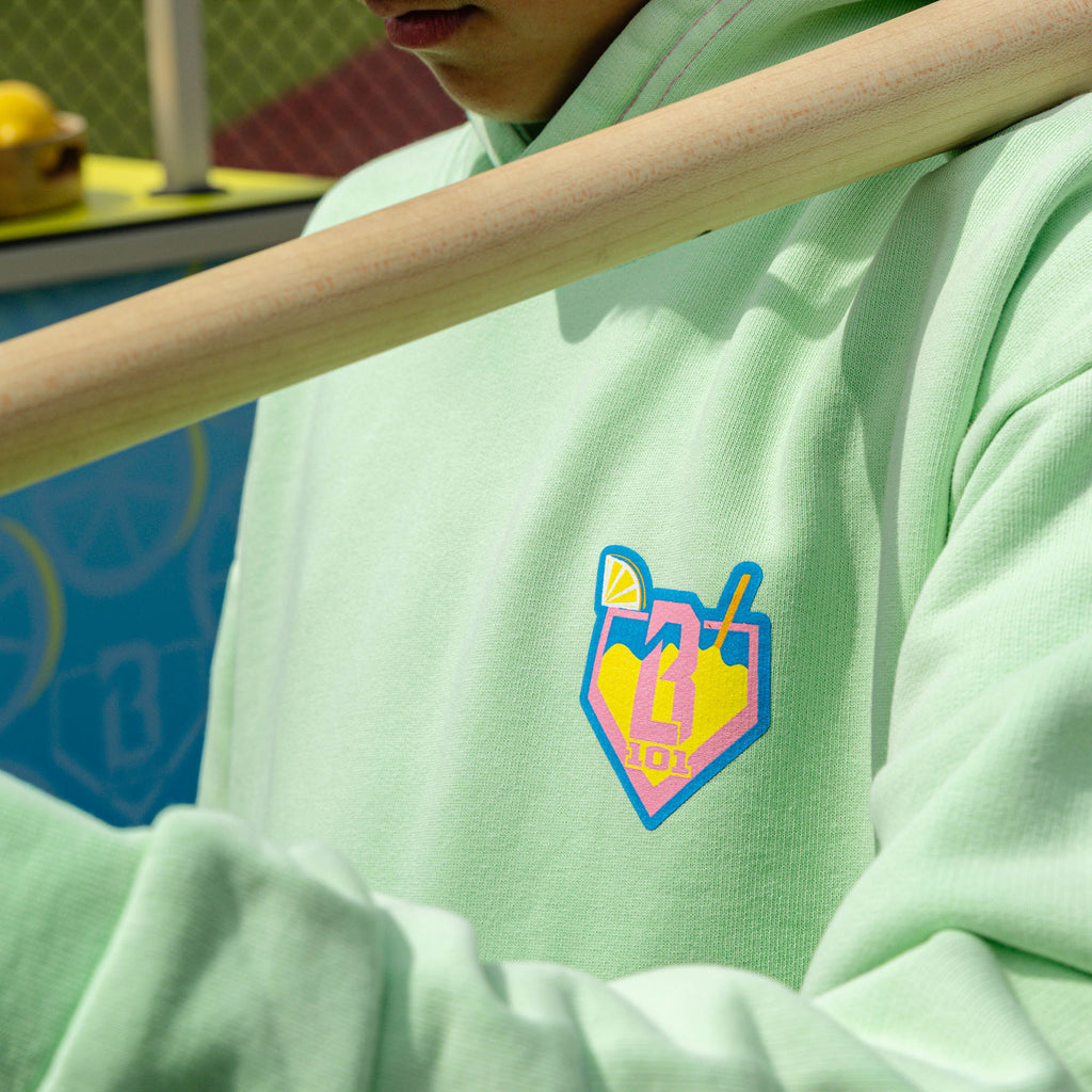 Youth model wearing green youth hoodie with "Lemonade" design