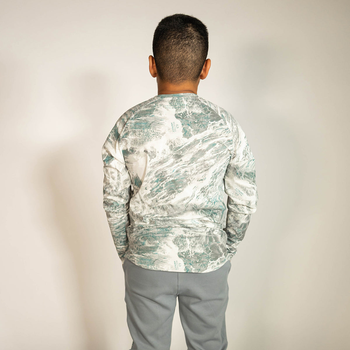 Youth model wearing gray Realtree Aspect Diamond Tech Camo youth long sleeve