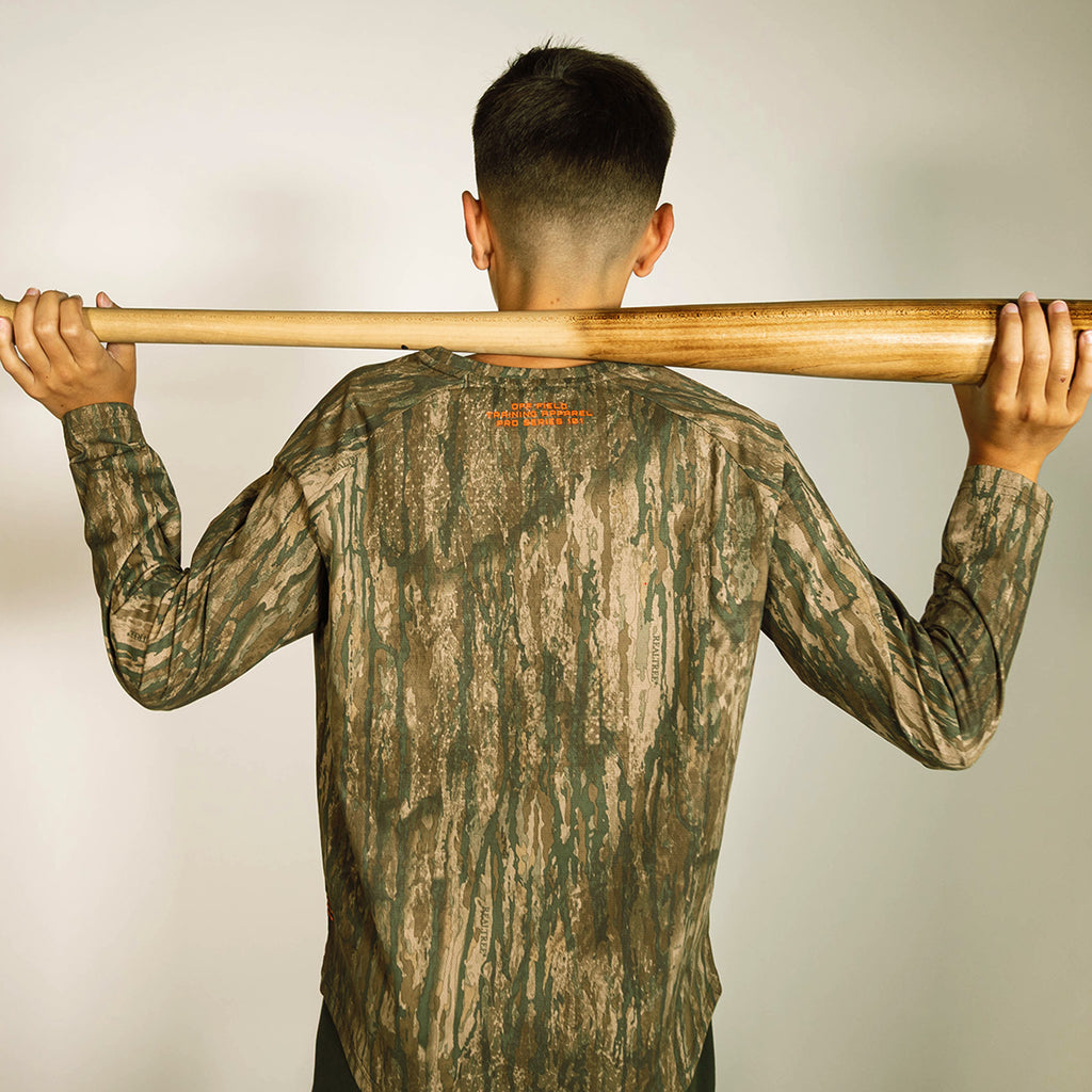 Youth model wearing multi-color Realtree Legacy Diamond Tech Camo youth long sleeve