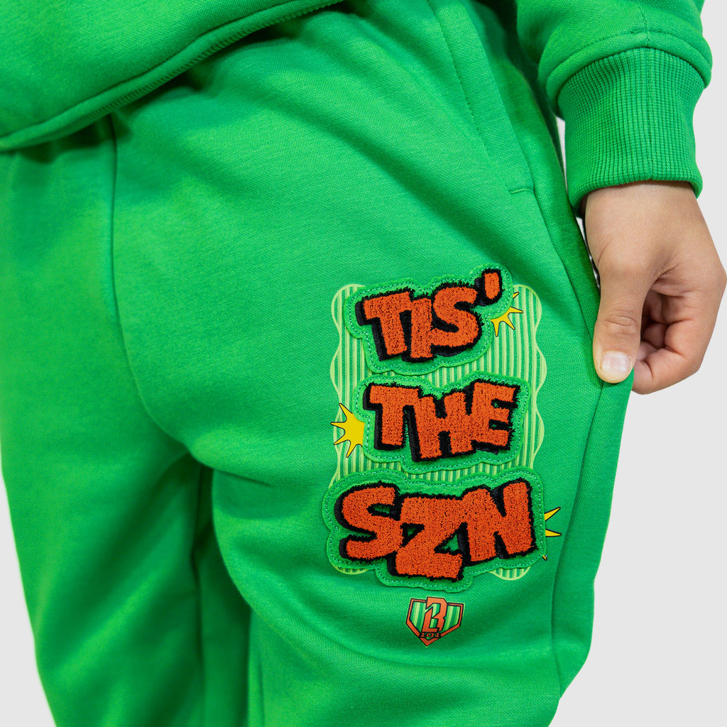 Youth model wearing green youth sweatpants with "Tis The SZN" design