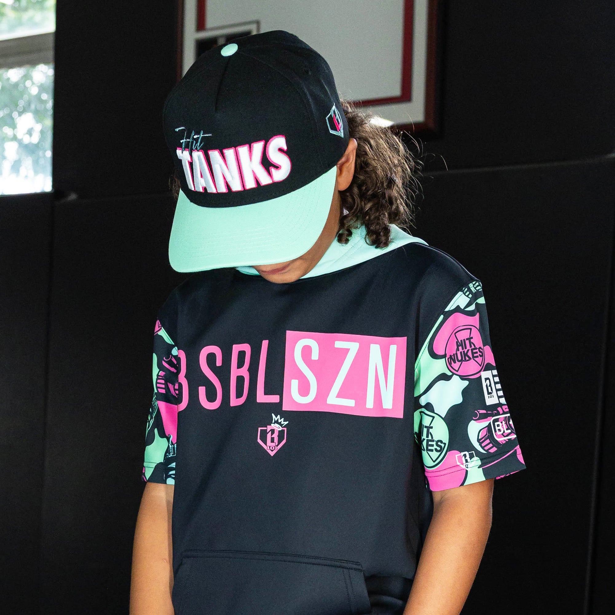 Youth model wearing black hat with "Hit Tanks" design