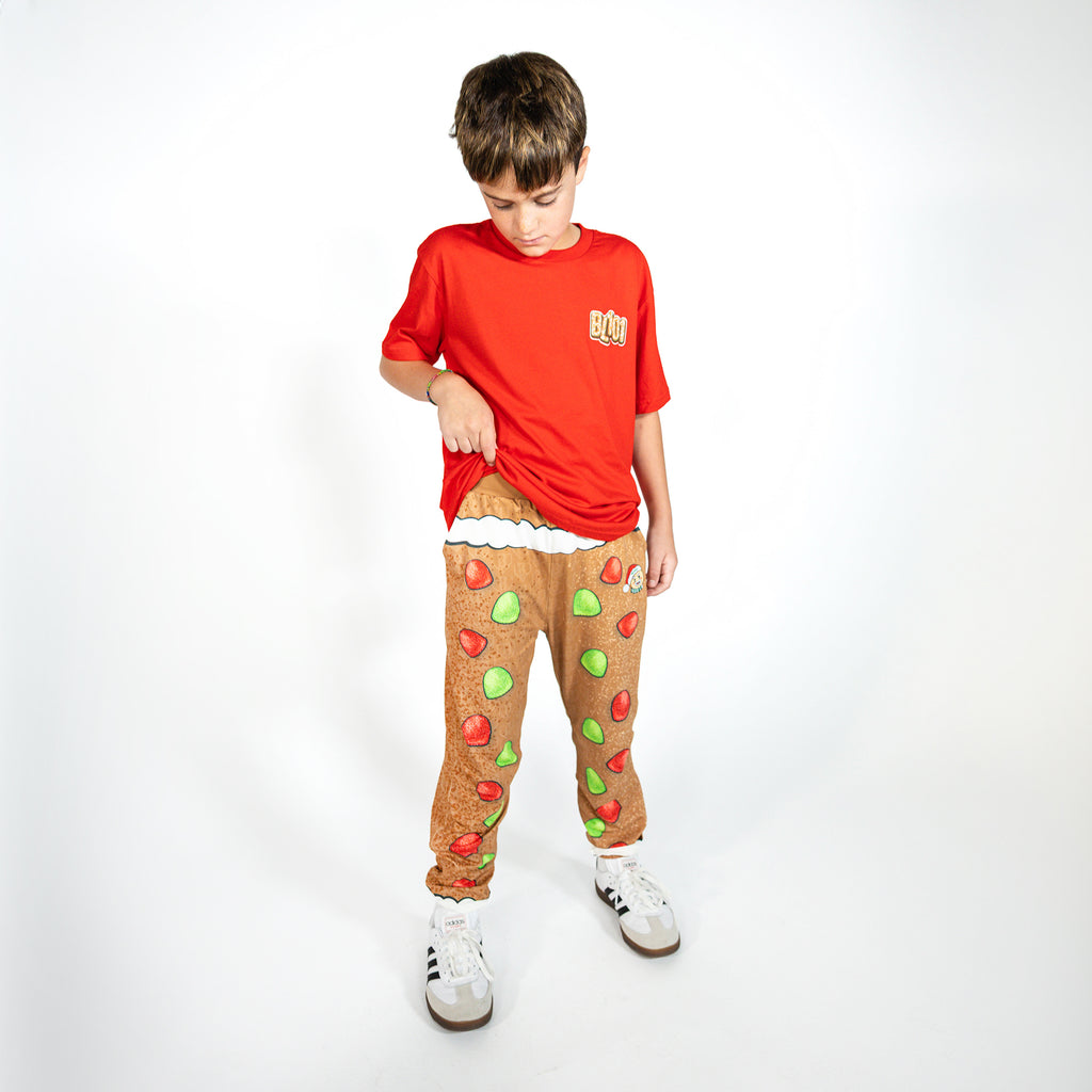 Youth model wearing brown youth pajama pants with "Gingerbread Rookie" design