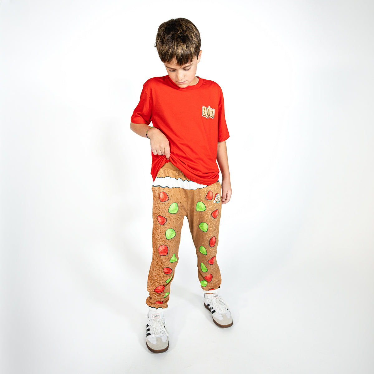 Youth model wearing brown youth pajama pants with "Gingerbread Rookie" design