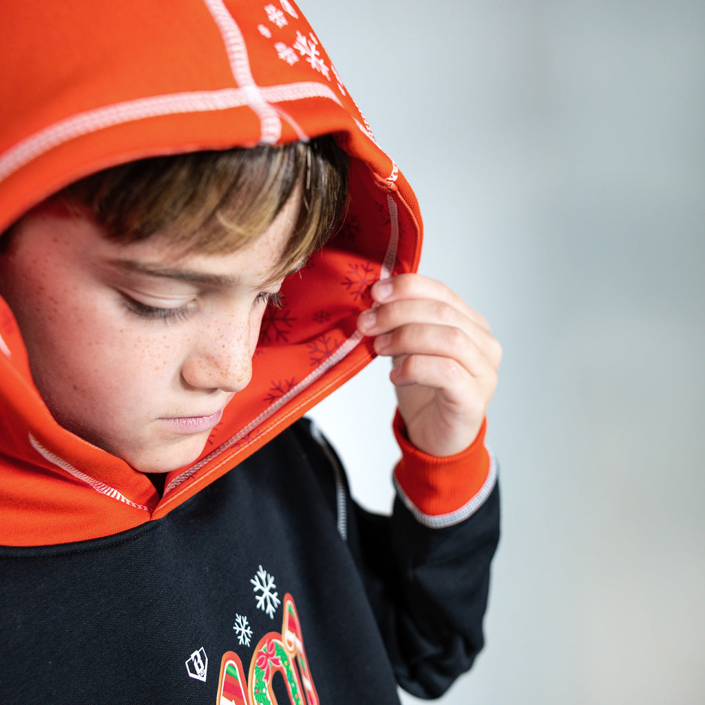 Youth model wearing black youth hoodie with "Holiday Cookie" design