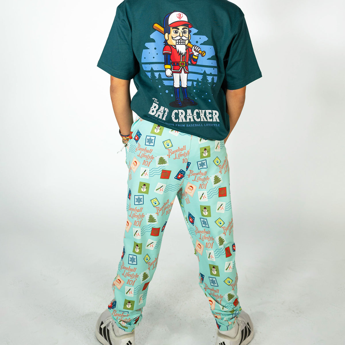 Youth model wearing teal youth pajama pants with "Holiday Stamps" design