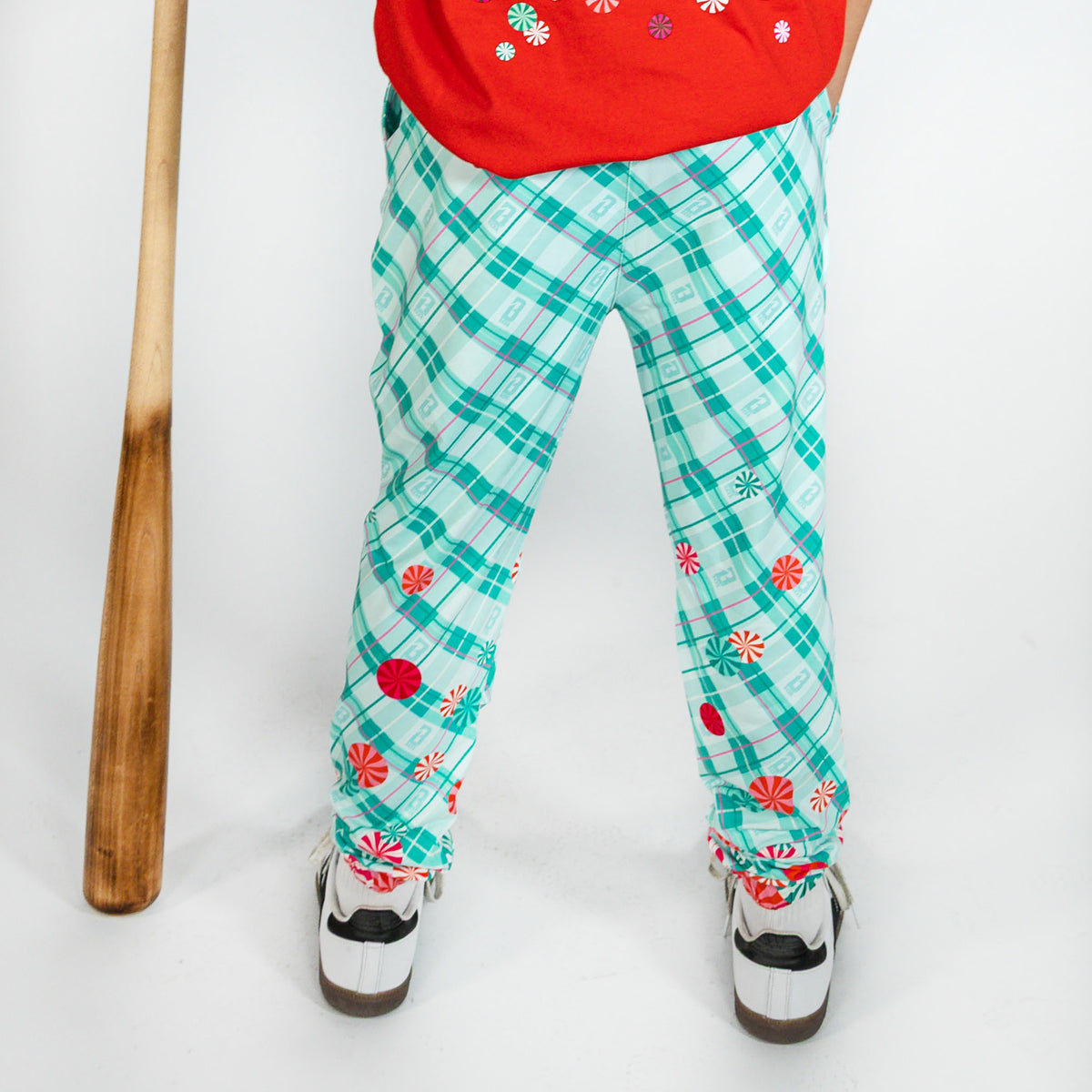 Youth model wearing multi-color youth pajama pants with "Peppermint Plaid" design
