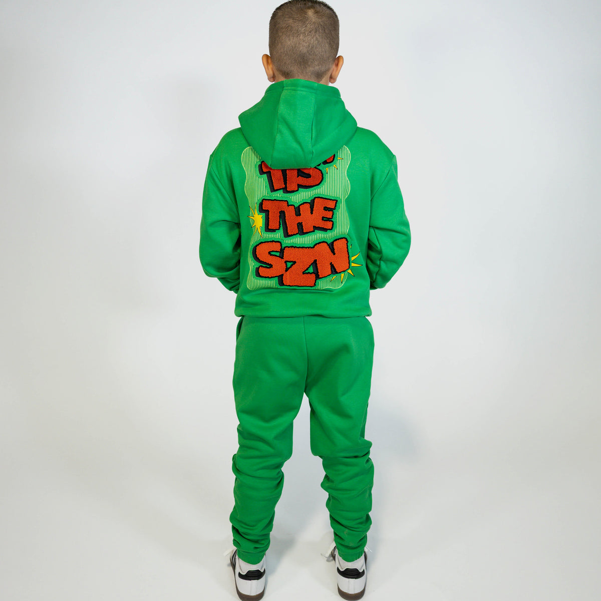 Youth model wearing green youth sweatpants with "Tis The SZN" design
