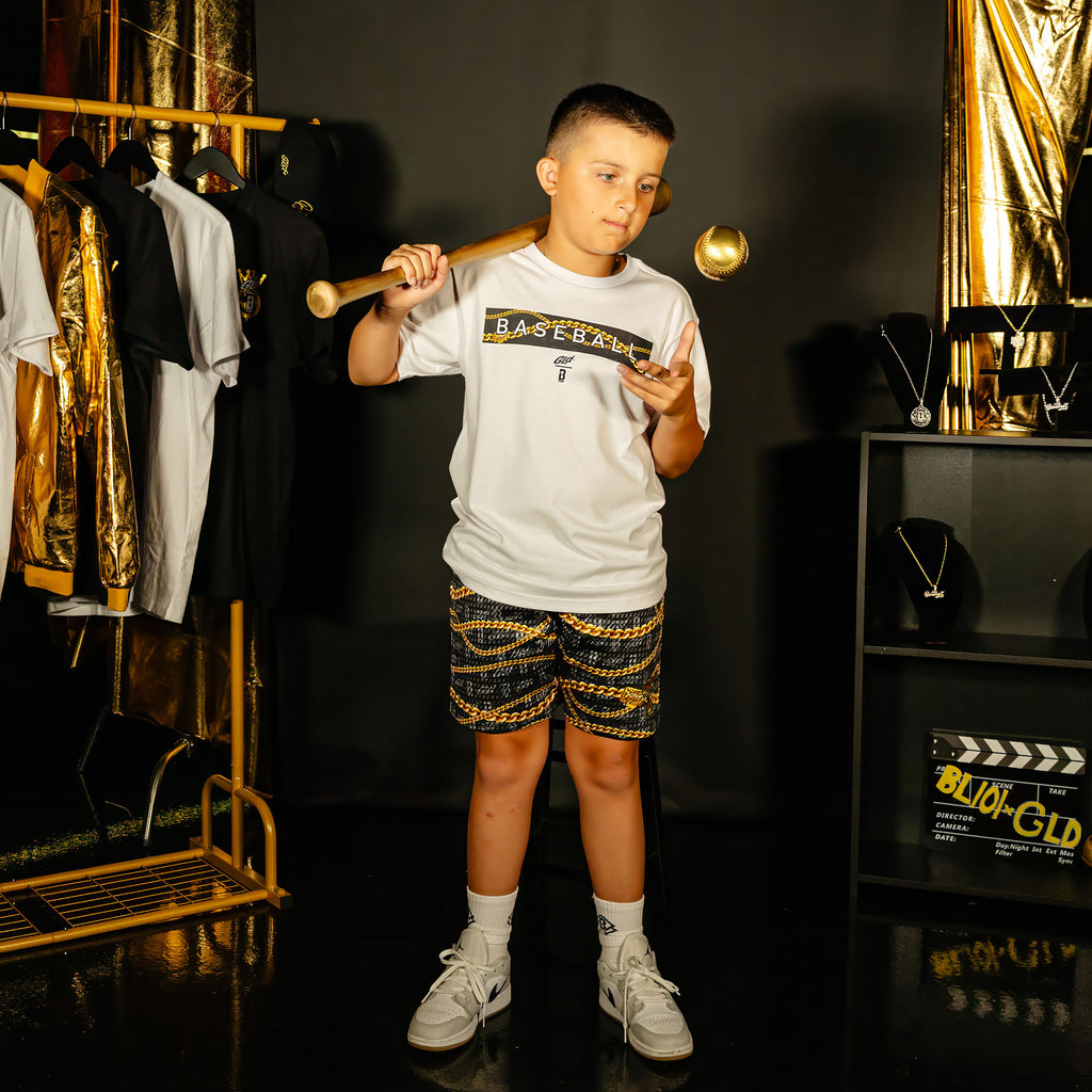 Youth model wearing black youth shorts with "BL101 X GLD" design