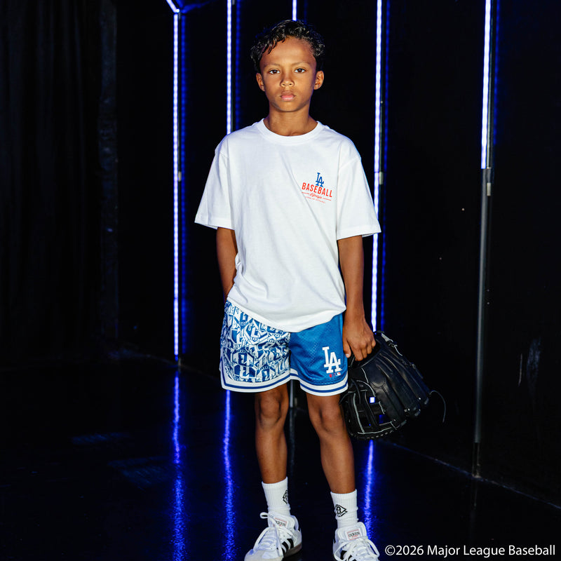 Youth model wearing blue youth shorts with "Los Angeles Dodgers Sticker Court" design