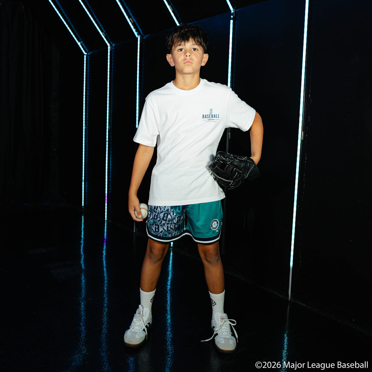 Youth model wearing green youth shorts with "Seattle Mariners Sticker Court" design