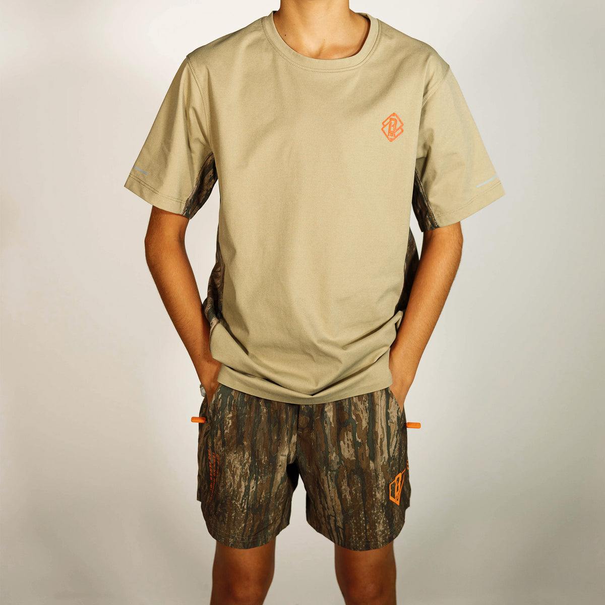 Youth model wearing multi-color Realtree Legacy Pro Series V2 Camo youth shorts with liner