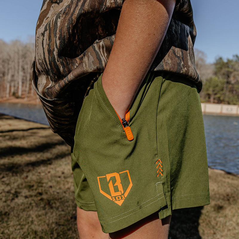 Person wearing green shorts with orange BL101 logo by a body of water