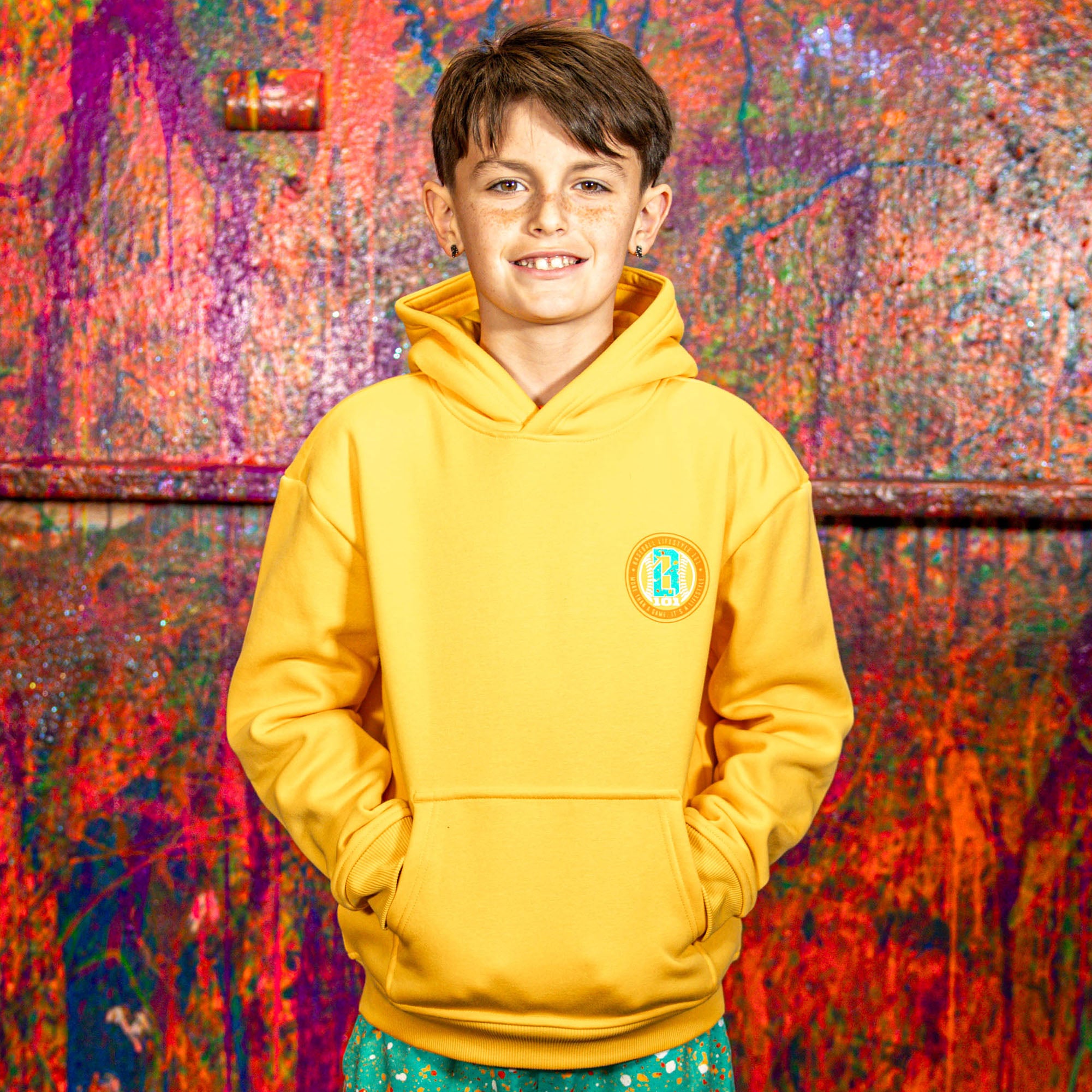 Child wearing a orange hoodie with a BL101 logo against a colorful, abstract wall.