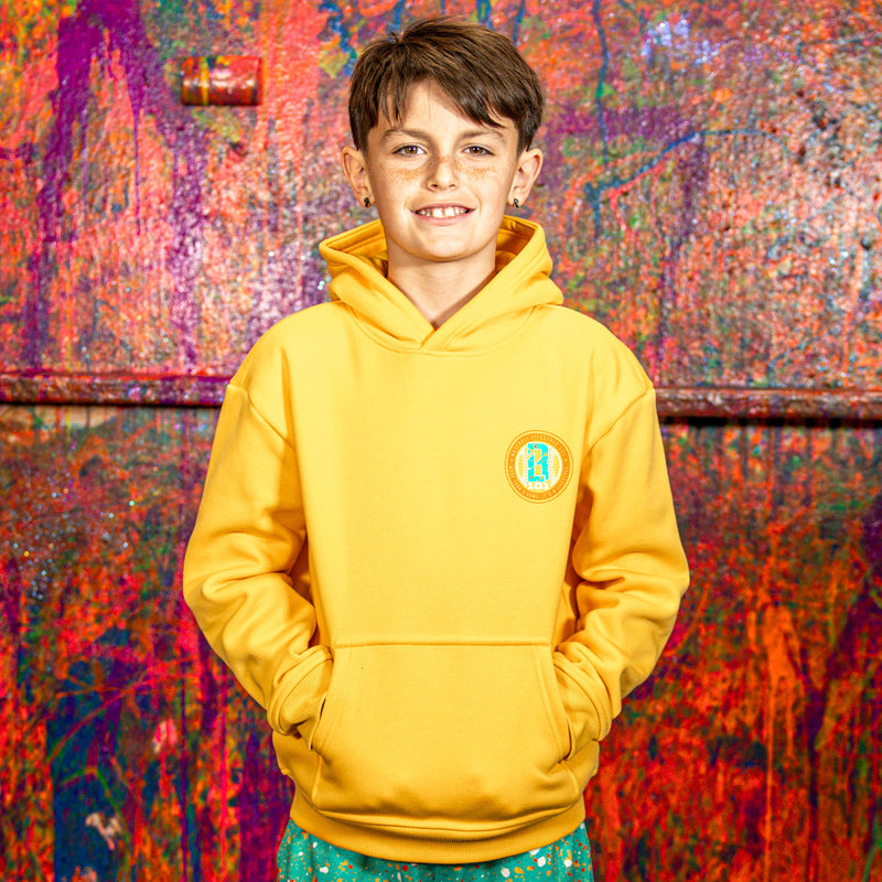 Child wearing a orange hoodie with a BL101 logo against a colorful, abstract wall.