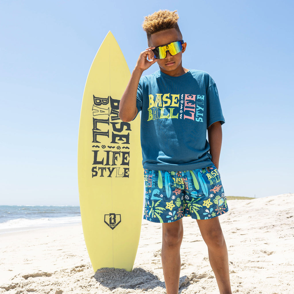 Youth model wearing blue youth graphic tee with "Surfside Slugger" design