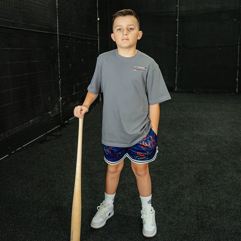 Child holding a baseball bat in an indoor batting cage