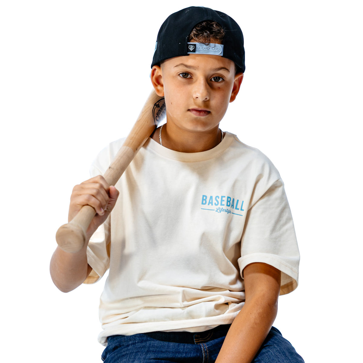 Child holding a baseball bat wearing a 'Baseball Lifestyle' t-shirt on a white background