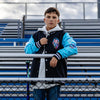 Person wearing a blue and black varsity jacket with a colorful ice cream cones, standing in bleachers.
