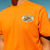 Orange t-shirt with a 'Where Dust Meets Diamond' logo on the chest against a blue sky.