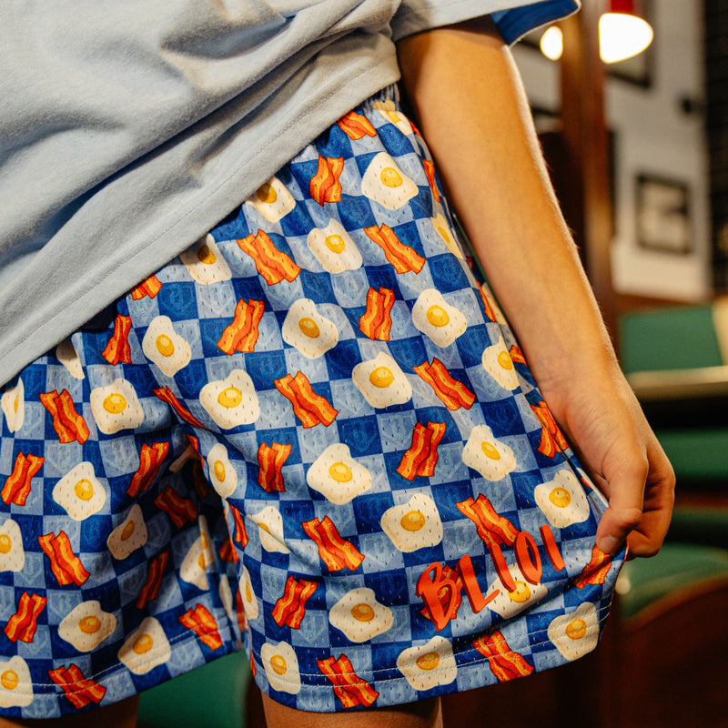 Person wearing a blue checkered skirt with bacon and egg pattern.