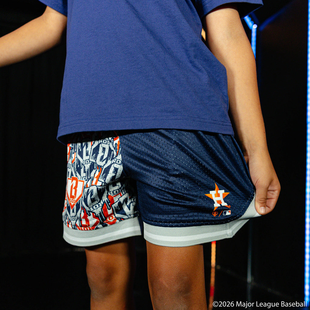 Youth model wearing blue youth shorts with "Houston Astros Sticker Court" design