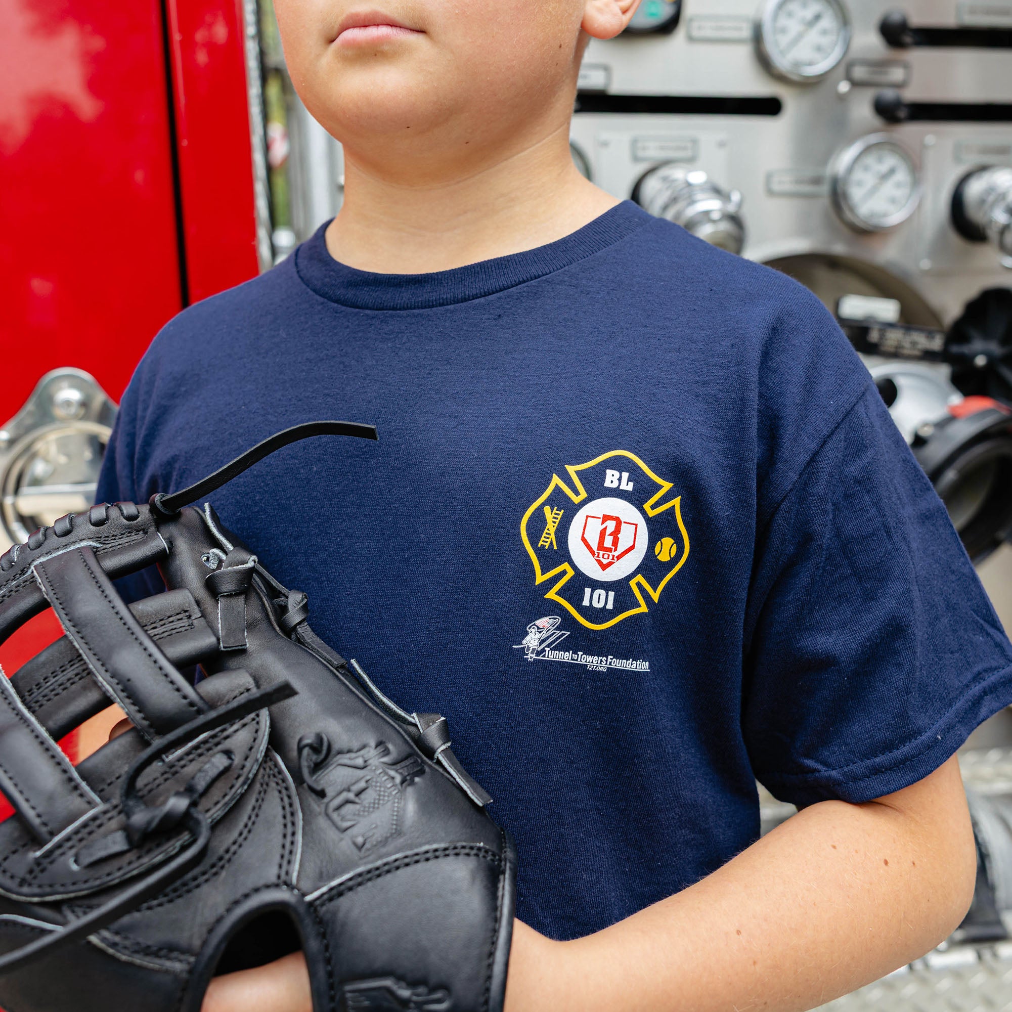 Youth model wearing Navy youth graphic tee with "BL101 X Tunnel to Towers Foundation" design