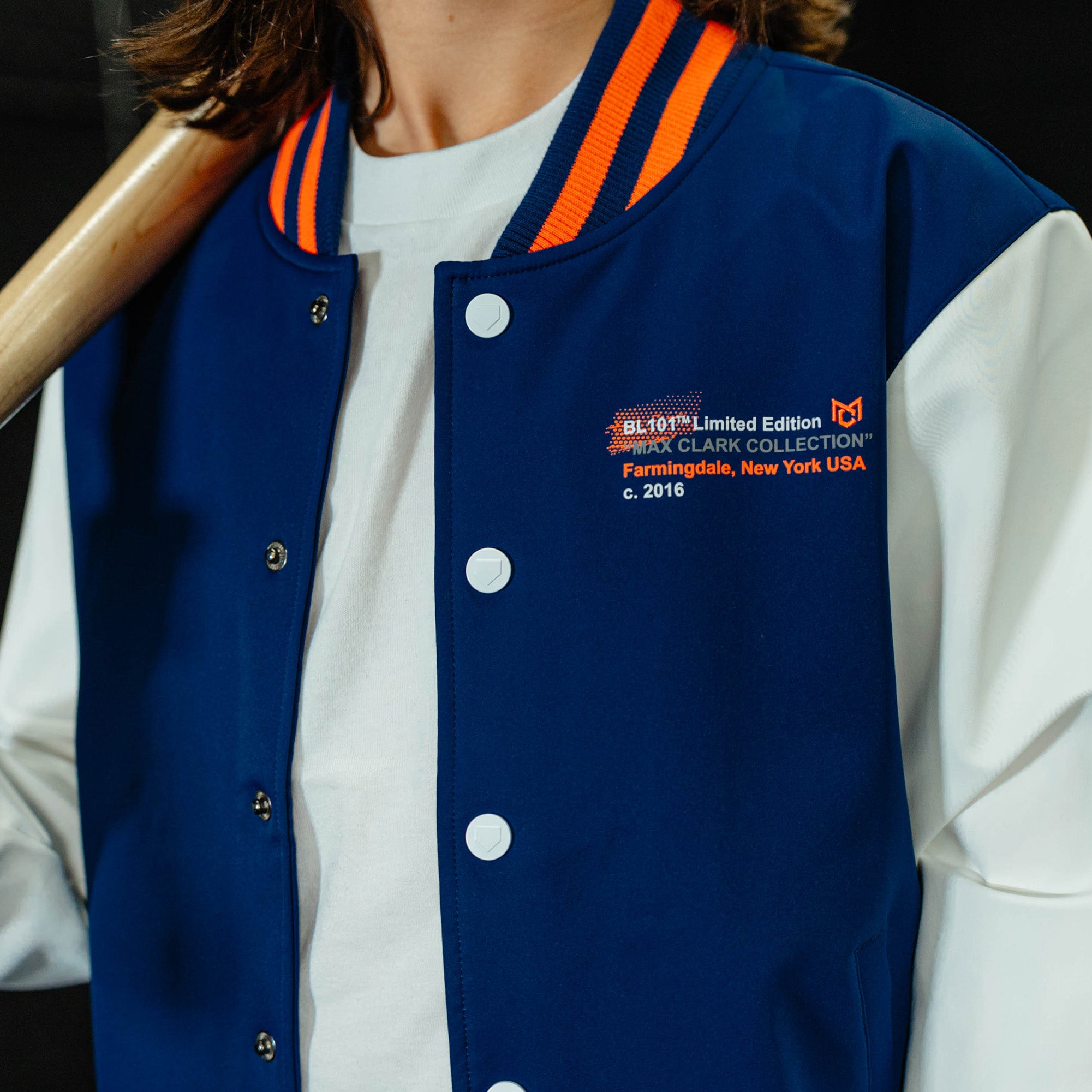 Blue letterman jacket with white accents and orange trim, featuring text on a black background.