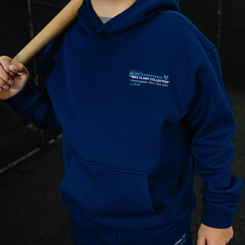 Person wearing a navy blue hoodie with branding, holding a wooden object.