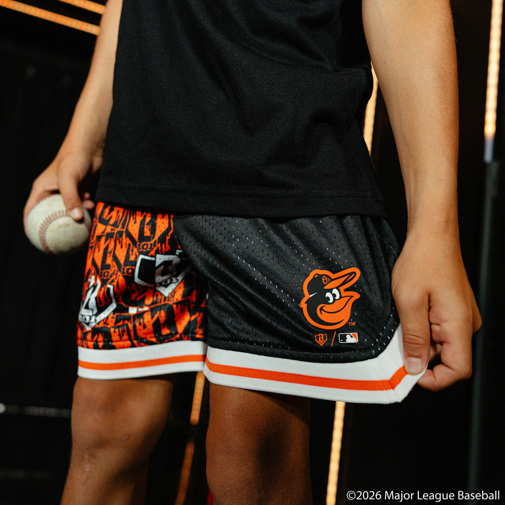 Youth model wearing black youth shorts with "Baltimore Orioles Sticker Court" design