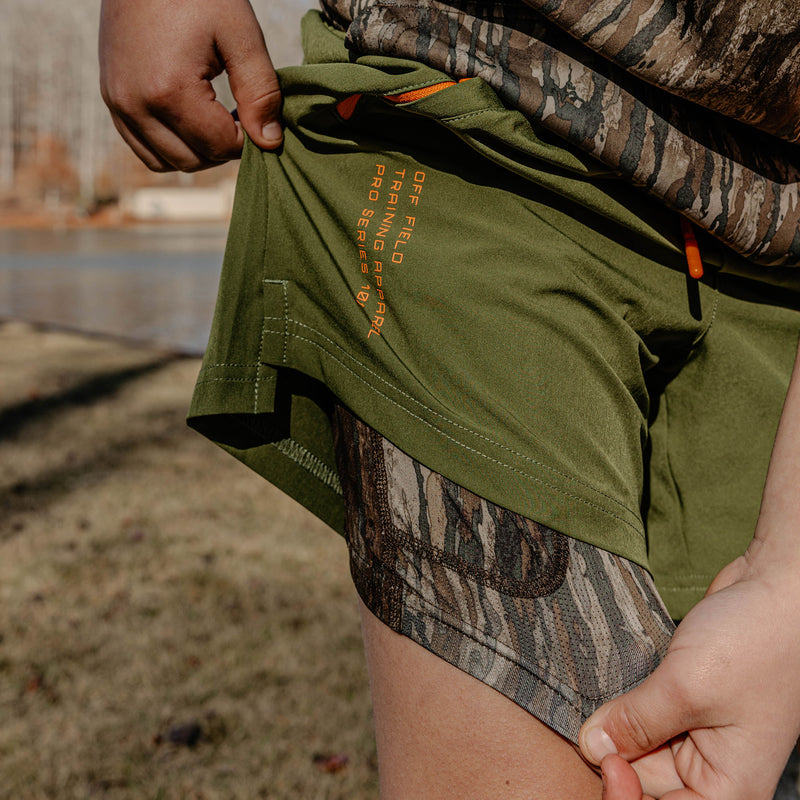 Person wearing green shorts with camouflage lining and 'OFF FIELD TRAINING APARREL PRO SERIES 101' text.