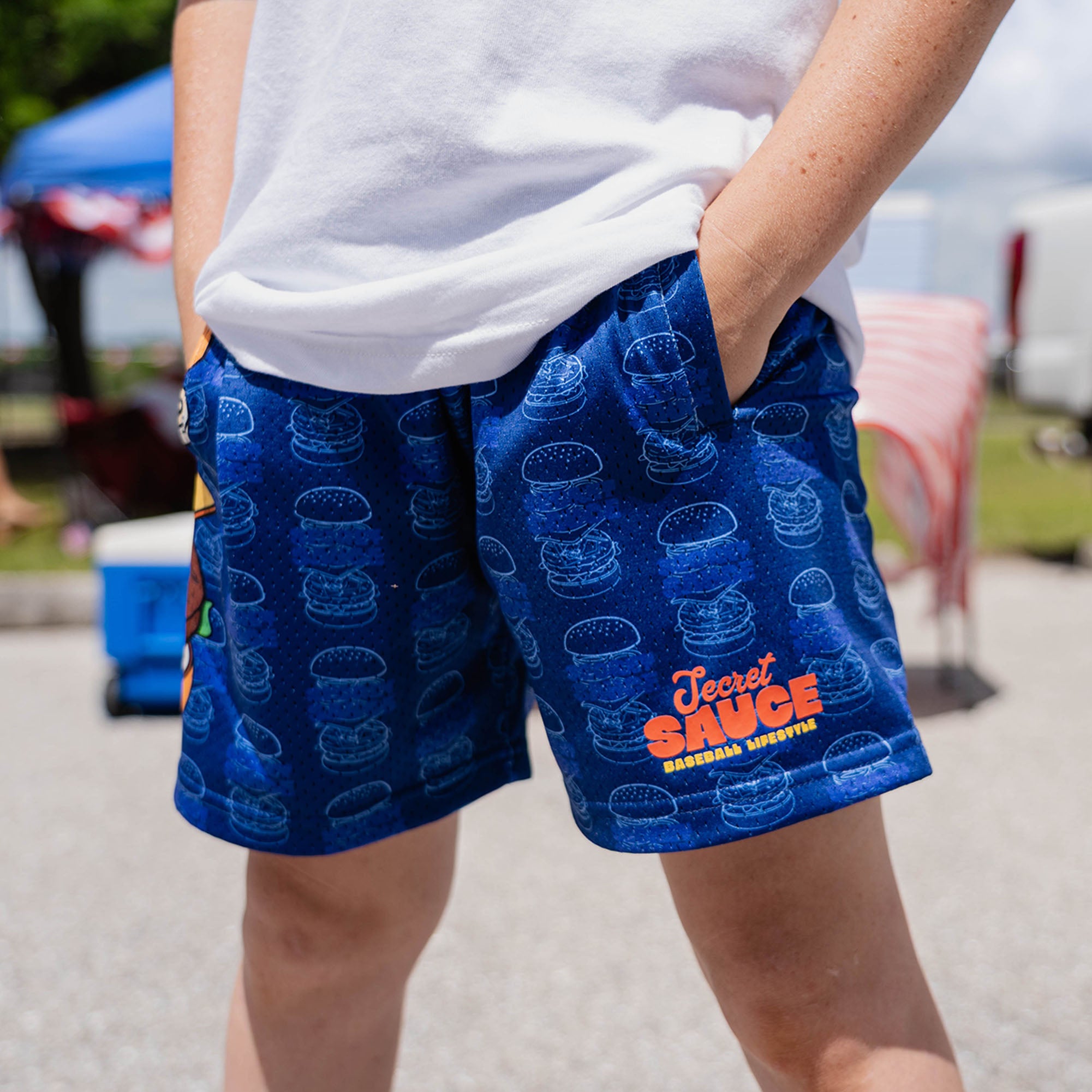 Lower body of male model wearing blue Secret Sauce burger print shorts