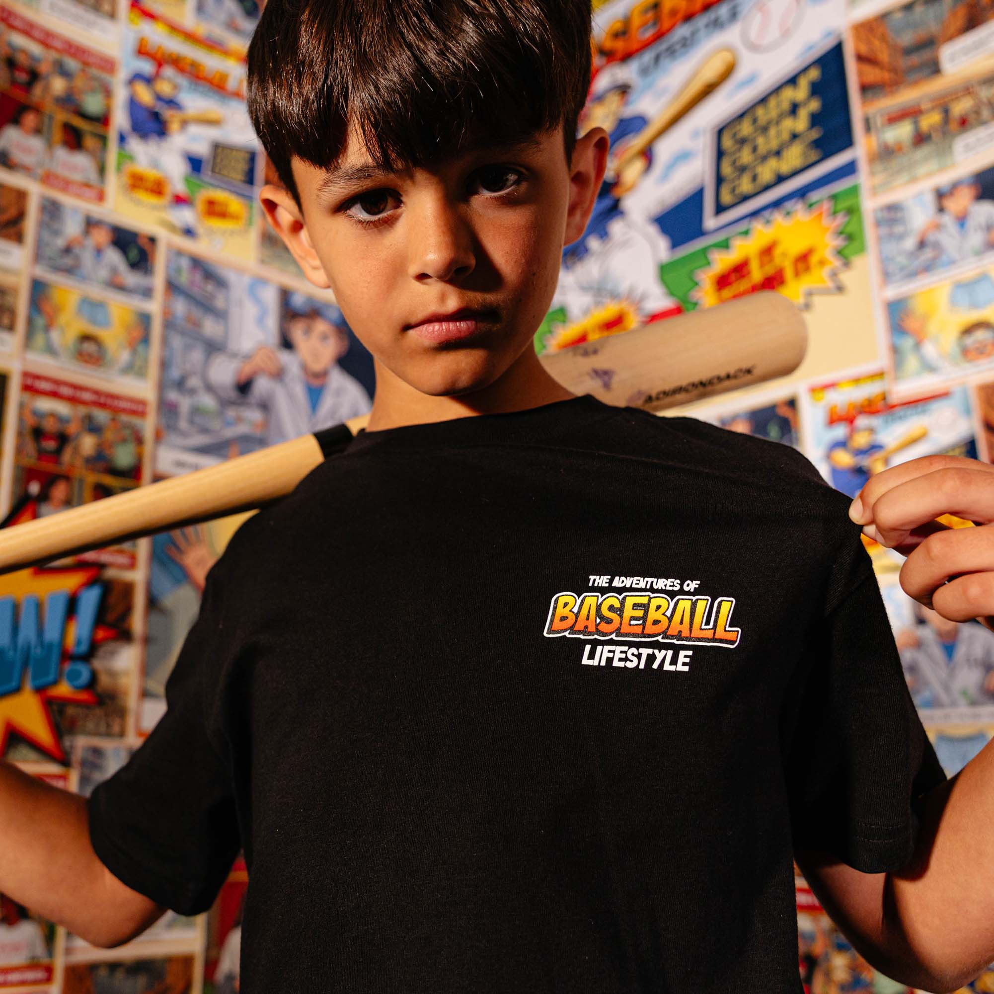Youth model wearing black youth graphic tee with "Swing For The Fences" design