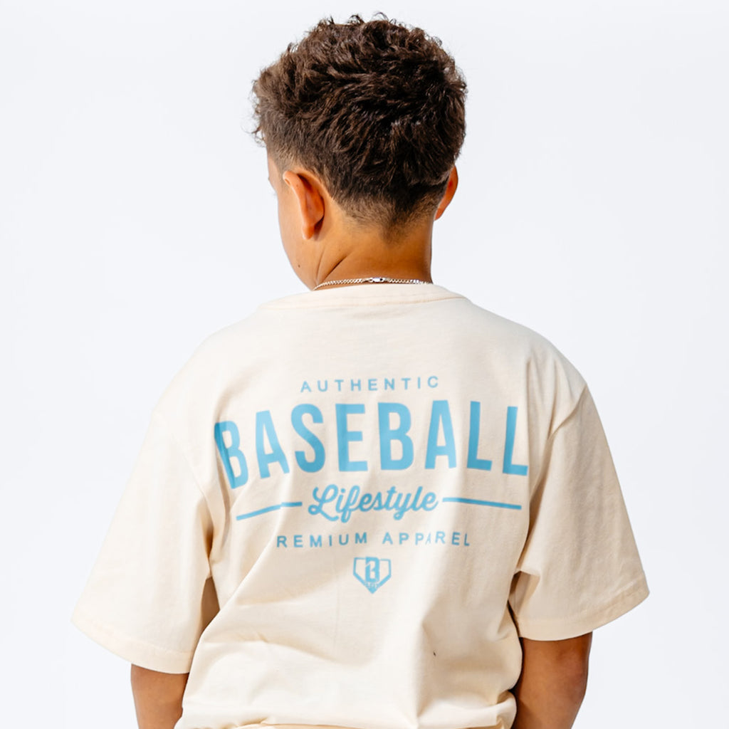 Child wearing a beige t-shirt with 'Baseball Lifestyle' text on the back against a white background