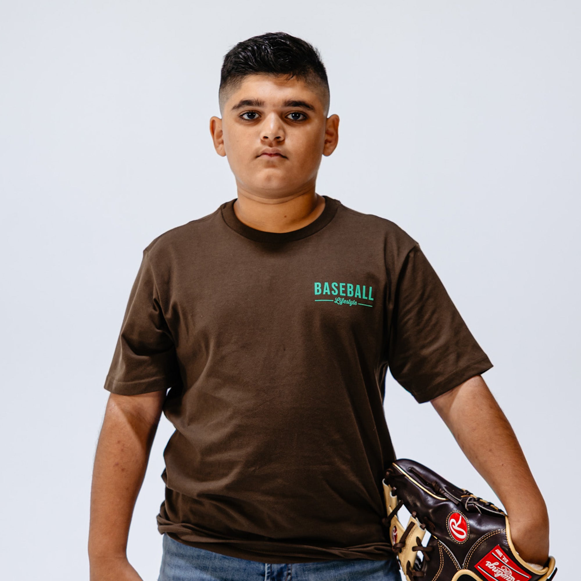 Person wearing a brown 'Baseball Lifestyle' t-shirt holding a baseball glove 