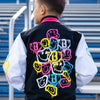 Person wearing a black varsity jacket with colorful smiley faces, and yellow BL101 logo standing in front of blue bleachers.