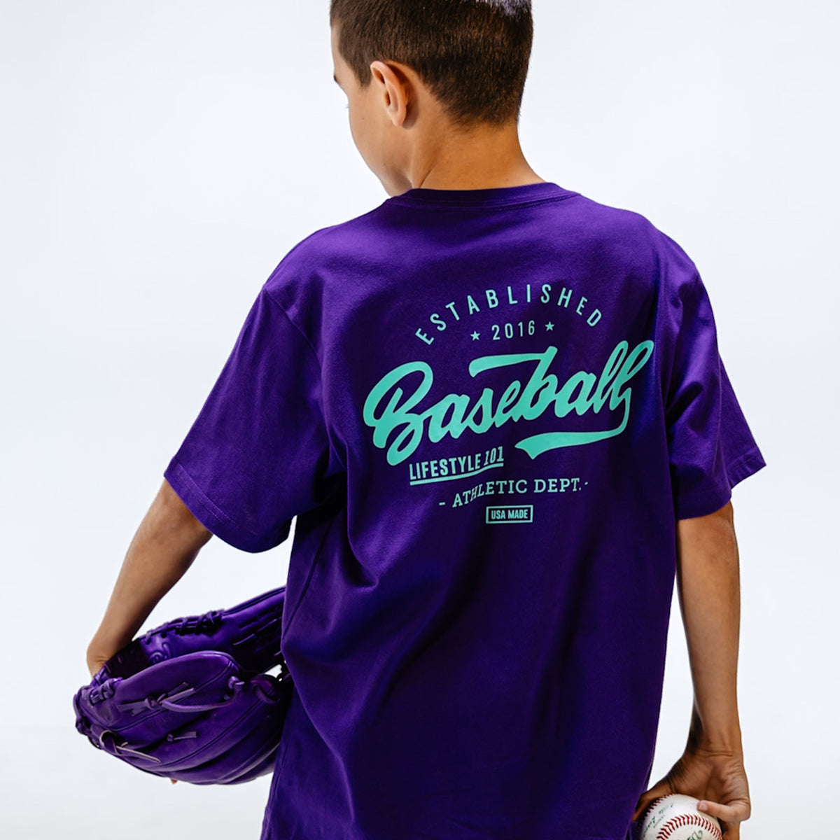 Person wearing a purple t-shirt with 'Baseball' text, holding a baseball glove and ball.