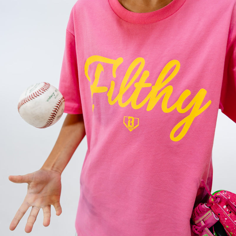 Person wearing a pink t-shirt with 'Filthy' printed in yellow, holding a baseball.