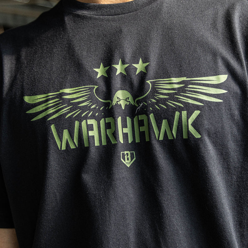 Close up of Youth black t-shirt featuring an army green eagle graphic with green “WARHAWK” lettering and a green Armor BL101 logo
