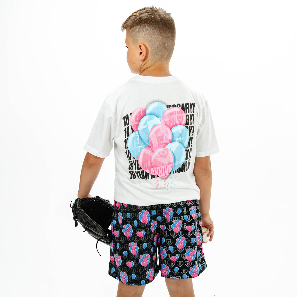Youth model wearing white youth graphic tee with "10 Year Anniversary" design