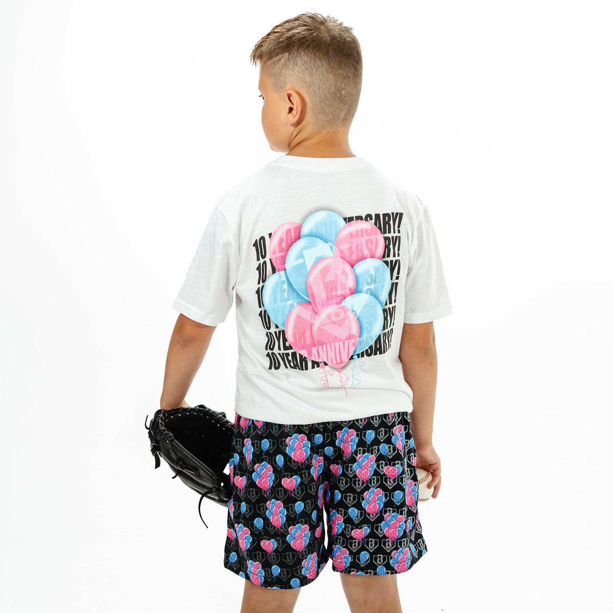 Youth model wearing white youth graphic tee with "10 Year Anniversary" design