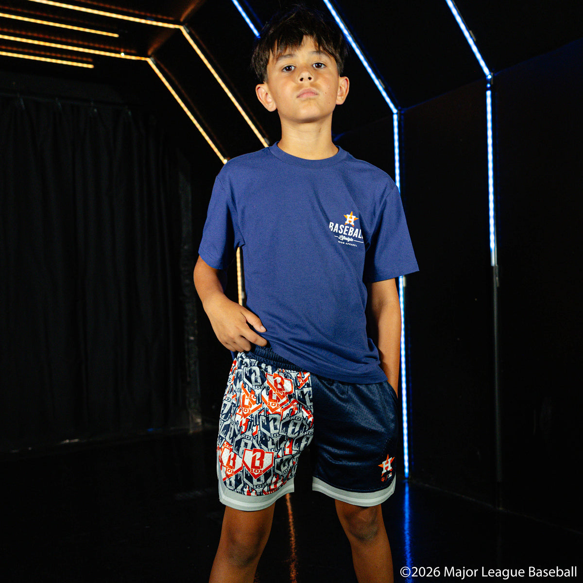 Youth model wearing blue youth shorts with "Houston Astros Sticker Court" design