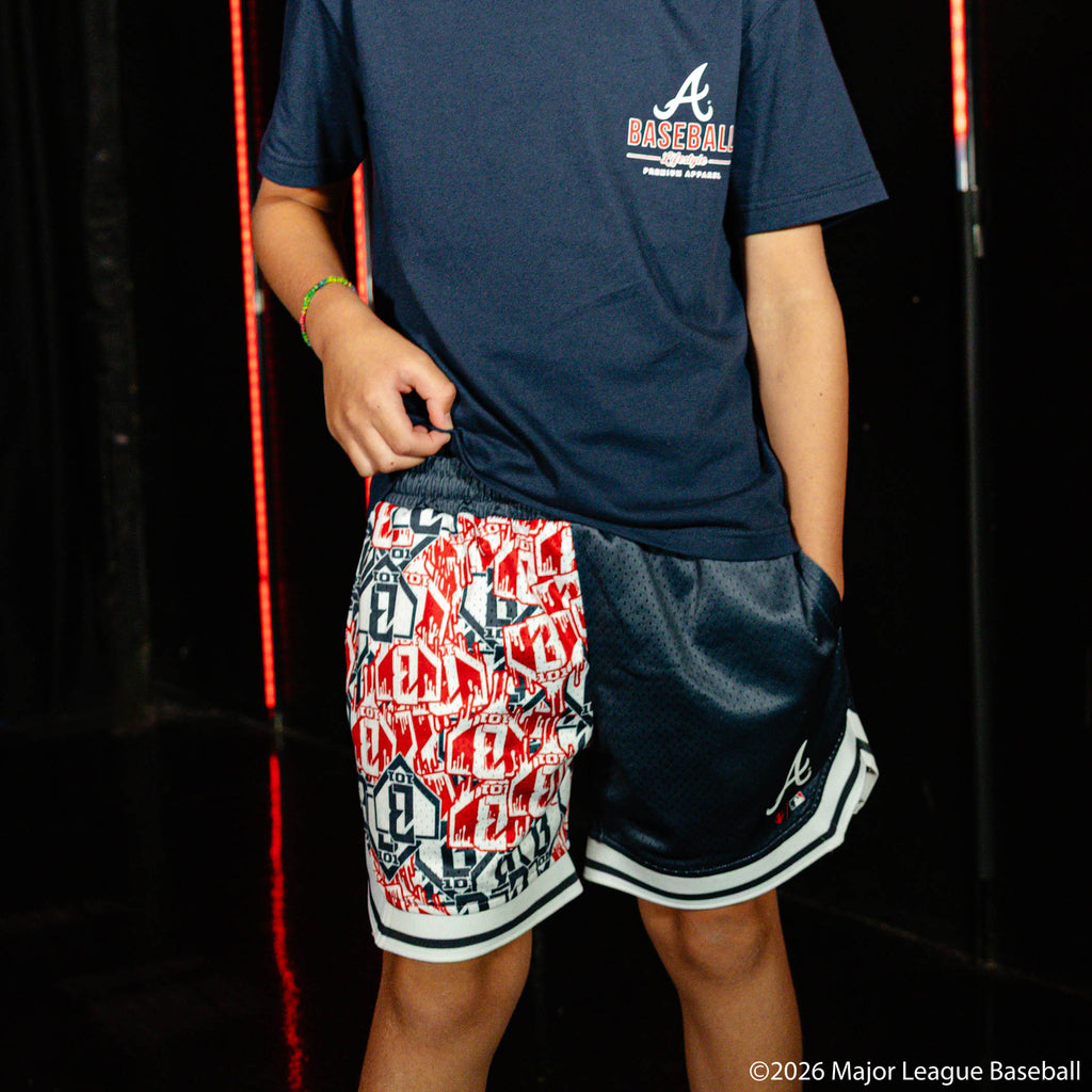 Youth model wearing navy youth shorts with "Atlanta Braves Sticker Court" design