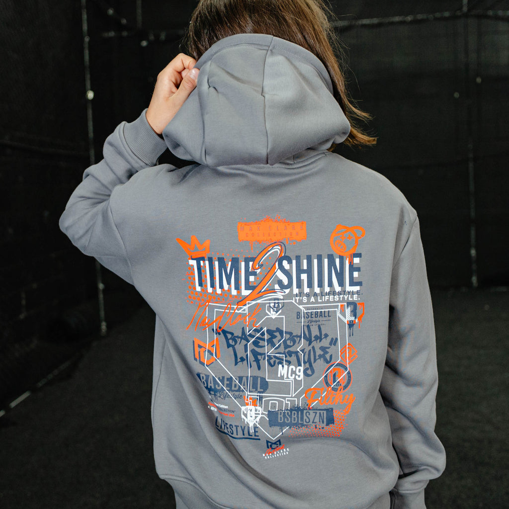 Person wearing a gray hoodie with colorful text and graphics on the back, standing against a dark background.