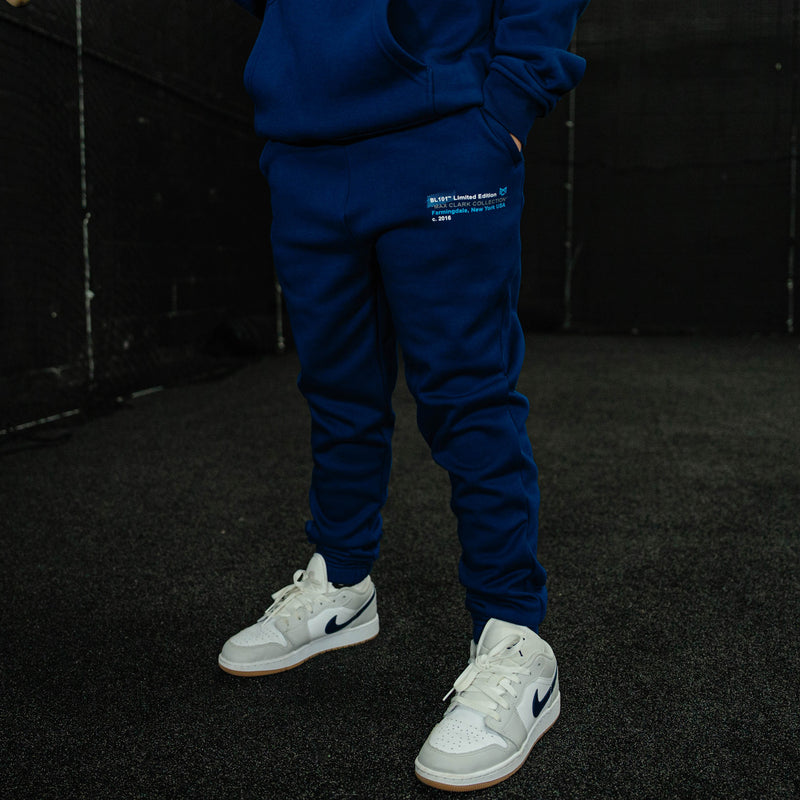 Person wearing a blue tracksuit with white sneakers on a dark background